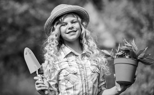 Happy childrens day. Happy childhood. Ranch girl. Planting plants. Little kid hold flower pot. Spring country works. Child in hat with shoulder blade small shovel hoe. Happy smiling gardener girl