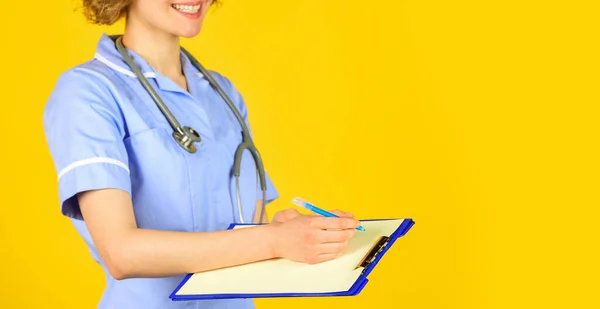 nurse in medical coat with documents writes important information. nurse writing some data into the folder of papers. Female hospital administrative in a modern medical center. copy space