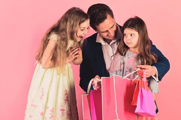 Skolflickor och far hålla rosa paket tittar inuti — Stockfoto