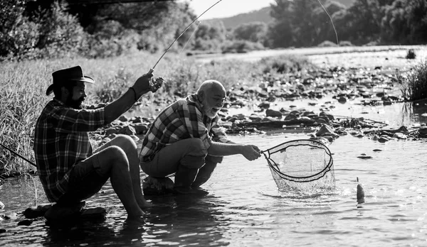 Voler poisson passe-temps des hommes. pêche à la retraite. Deux amis mâles pêchant ensemble. père à la retraite et fils adulte. heureux pêcheurs amitié. pêche au gros gibier. relaxer sur la nature. Grande journée pour la pêche — Photo