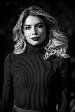 Kadınlık ve şefkat. Sonbahar tarzı kıyafetler. Sonbahar modası. Sevimli kız geçen güneş ışınlarının tadını çıkarıyor. Şık kıyafetler. Sonbahar parkında yürüyen bir kadın. Samimi örgü giysiler. Örgü süveter