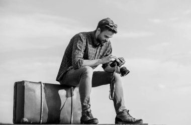 Adam bavula oturur. Gezgin blogcu. Yakışıklı gezgin geçmişe dönük kamera. Bagajla seyahat et. Video bloğu çekiliyor. Tatil zamanı. Klasik valizli bir adam. Fotomuhabir konsepti. Seyahat günlüğü