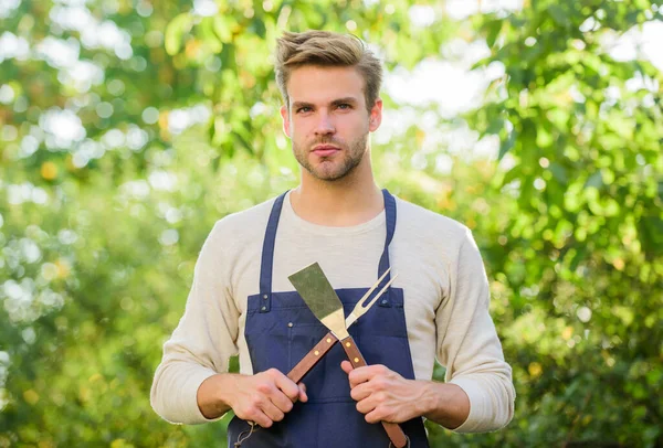 Grillen. Grillutensilien. Burger kochen. Der Mann hält Grillgeräte in der Hand. Sommerwochenende. Werkzeuge zum Braten von Fleisch im Freien. Grillparty. Picknickkonzept. Bbq Koch. Schöner Typ, der Essen kocht — Stockfoto