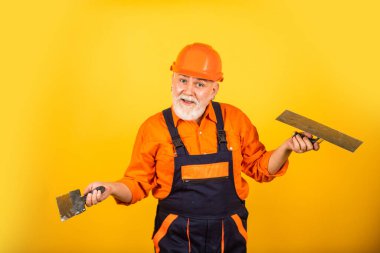 Sanırım sana yardım edebilirim. Alçıpan alçıpanında alçıpan spatulası. Üniformalı sıvacı. Spatulalı adam. Macun katmanının uygulanması işlemi. Sıva için alçı araçları