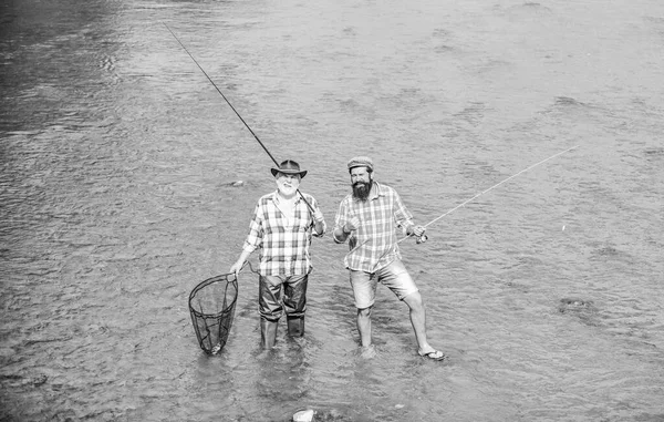 Never Too Far For Family. summer weekend. mature men fisher. male friendship. family bonding. father and son fishing. two happy fisherman with fishing rod and net. hobby sport activity. Trout bait