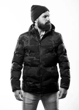 Sakallı adam beyaz arka planda izole edilmiş sıcak kamuflaj desenli ceket giyiyor. Hipster kış modası. Şapka takan ve siyah kışlık ceket giyen adam. Rahat bir kış kıyafeti. Kış stili erkek giyim