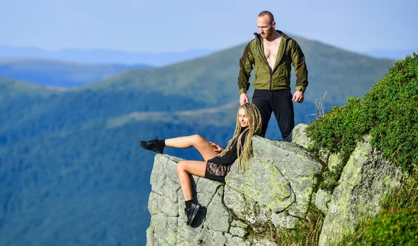 Couple hikers enjoy view. Hiking benefits. Hiking weekend. On edge of world. Woman sit edge of cliff high mountains landscape background. Hiking peaceful moment. Tourist hiker girl and man relaxing