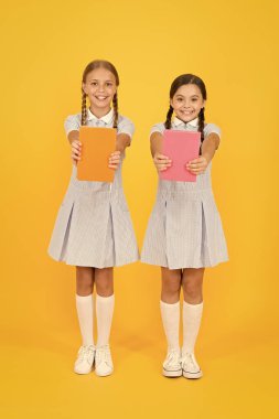 Okul kütüphanesi. Evde eğitim konsepti. Okuryazarlık kulübü. Sarı arka plan üzerine kitaplar tutan sevimli çocuklar. Ansiklopedisi ya da çocuk kitapları olan küçük kızlar. Okullar için eğitim kitapları. Kitap okuma