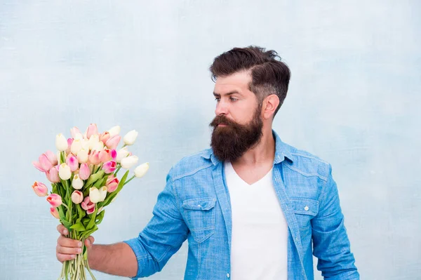 man with bouquet of tulips for her. fresh spring flowers. Concept of greeting mothers and fathers day. Valentines day gift for woman. bearded hipster hold bouquet of tulips. love and surprise concept