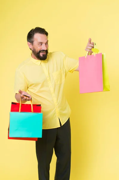 Faire du shopping et profiter. Shopping accro fond jaune. Homme mûr tenir des sacs à provisions. Joyeux client avec des sacs en papier. Vente et achats. Faire du shopping comme il se doit, copier l'espace — Photo