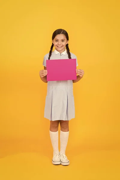 Lis ça. Prochain événement. Robe de fille bien rangée tenir affiche. Écolière tenir affiche copie espace. Des infos. Changements à venir. Retour à l'école. Affiche d'écolière. Promotion des produits — Photo