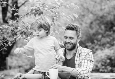 Yaz kahvaltısı. Sağlıklı gıda kavramı. Baba oğul yemek yer ve eğlenir. Çocuklar için menü. Aile ev yapımı yemeklerin tadını çıkarır. Yemek alışkanlıkları. Baba gıda piknik bahçesinde doğa arka plan yeme ile küçük çocuk