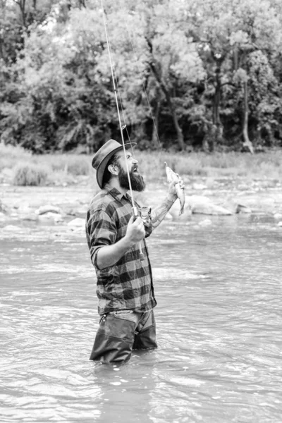Brutal man wear rubber boots stand in river water. Weekend activity. Fishing masculine hobby. Fishing requires you to be mindful and fully present in moment. Fisher fishing equipment. Fish on hook — Stock Photo, Image