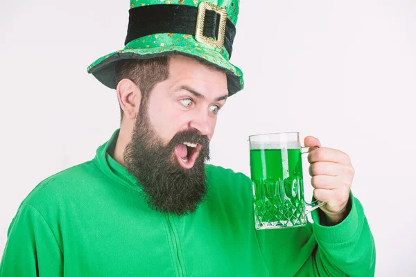 Celebrando el día de San Patricio en el bar. Un irlandés con barba bebiendo cerveza verde. Hipster en sombrero de duende sosteniendo taza de cerveza. Un hombre barbudo brindando por el día de San Patricio. Vamos a prepararnos para murmurar — Foto de Stock