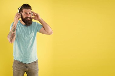 DJ, bırak müzik çalsın. DJ sarı arka planda. Sakallı adam DJ kulaklıklarıyla müzik dinliyor. Hipster DJ performansı için kablosuz kulaklık kullanıyor. Radyo disk jokeyi. Kulüp veya müzik festivali, kopyalama alanı