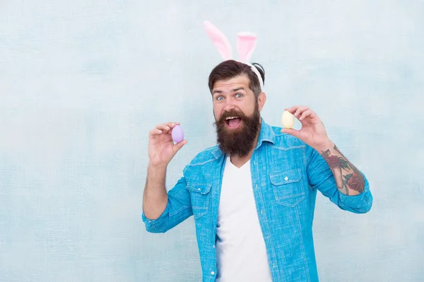 Everything you need for Easter is here. Hipster long ears holding egg. Culture customs and traditions. Easter bunny colored eggs. Celebration of spring holiday. Bearded man bunny ears and Easter eggs