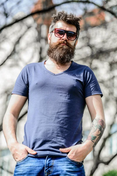 Man bearded with sunglasses nature background. Bearded man wear modern fashionable sunglasses. Hipster confident in dark sunglasses. UV filter. Bearded hipster brutal man wear protective sunglasses