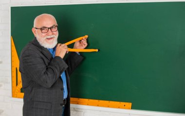 Usta öğretmen pusula kullanıyor. Sakallı özel öğretmen tahtasında pusula ile çizer. Okula dönüyorum. Matematik aletleri konsepti. Bilgiye doğru. İyi sonuçlar almak için matematik çalış. Boşluğu kopyala