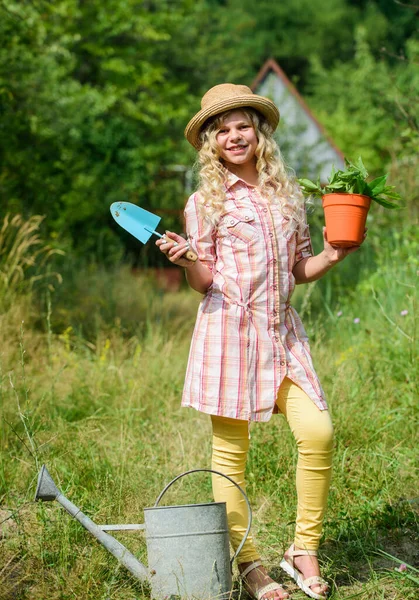 Child in hat with shoulder blade small shovel hoe. Happy smiling gardener girl. Little kid hold flower pot. Spring country works. Happy childrens day. Ranch girl. Happy childhood. Planting plants — Stock Photo, Image