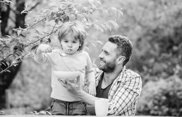 Summer breakfast. Healthy food concept. Feeding baby. Menu for children. Family enjoy homemade meal. Father son eat food and have fun. Food habits. Little boy with dad eating food nature background — Stock Photo, Image