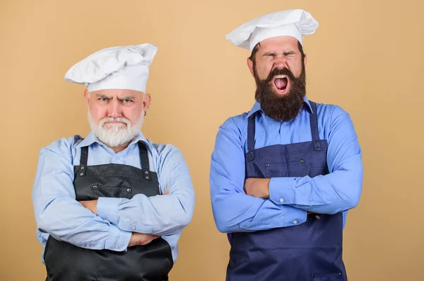 Family restaurant. Chef men wear aprons. Father and son culinary hobby. Cafe workers. Restaurant kitchen. Culinary industry. Restaurant staff. Mature bearded men professional restaurant cooks