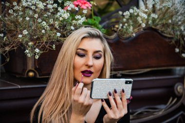 Makyaj videosu izleyen bir kız. Dudakta ruj izi. Kozmetik ve makyaj malzemeleri. Randevuya hazır ol. Her zaman iyi görünüyorsun. Akıllı telefon aynası. Kozmetik inceleme kanalı. Güzellik blogcusu kavramı. Makyaj uygula