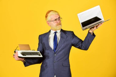 Yeni modern aletler al. Yararlı bir cihaz. Modern yerine modası geçmiş. Vintage değerler uzmanıyım. Dizüstü bilgisayara karşı daktilo. İş adamı modern teknolojiyi kullanır. Adam sakallı, saçları sarıya boyanmış.