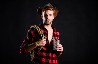 Her zaman nehrin yukarısındaki sürüden iç. Klasik tarz adam. Vahşi Batı eski kovboy. Kement ipli bir kovboy. Batı. Vahşi batı rodeosu. Siyah şapkalı adam. Çiftlikte kareli gömlek