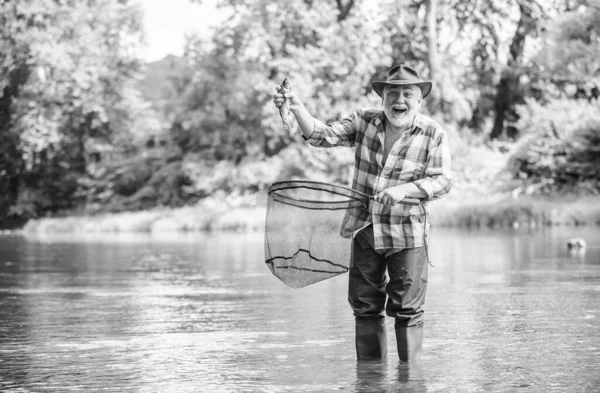 漁師の釣り道具。趣味のスポーツ活動。年金生活者の余暇。商業的に魚を飼育する魚の養殖ピシカル。漁師だけが川の水の中に立っている。男シニアひげ漁師 — ストック写真