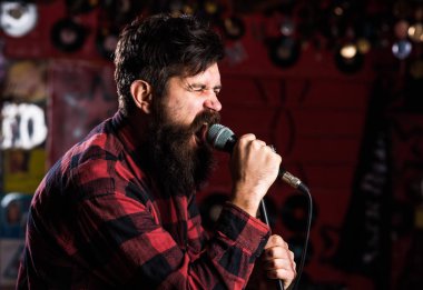 Sahnede mikrofonlu kaba sakallı şarkıcı. Rock yıldızı konsepti. Adam agresif bir şekilde şarkı söylemeyi seviyor. Gergin suratlı adam mikrofonu tutuyor, şarkı söylüyor, karaoke kulübü geçmişi var..