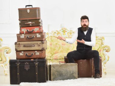 Şaşırmış suratta maço şıklığı, toplanmanın sonunda kafası karışık, antika bavulların yanında. Bıyıklı, sakallı, bavullu, beyaz arka planlı bir adam. Bagaj ve taşınma konsepti.