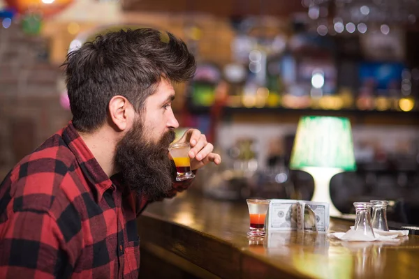 Hombre con barba bebe alcohol en el bar sobre fondo borroso . —  Fotos de Stock