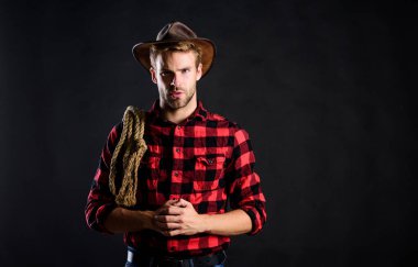 Lasso, rodeo yarışmaları kullanırdı. Kementle bağlanabilir ya da paketlenebilir. Acımasız ve kendinden emin. Batı hayatı. Erkek traşsız kovboy siyah arka planı. Şapka tutan adam. Amerikan kovboyunun kementi.
