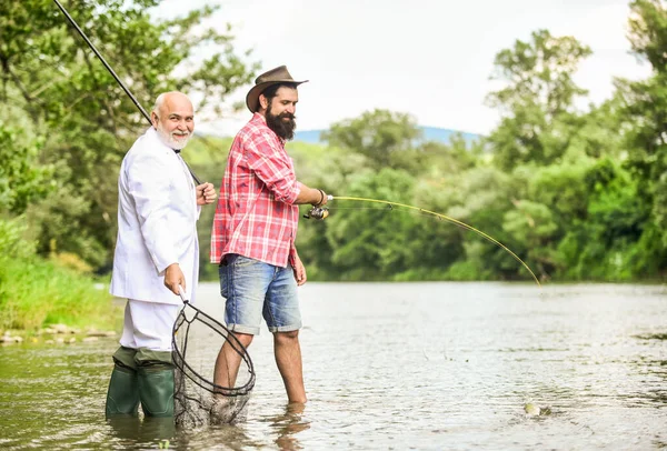 Gone Fishing. hobby of businessman. retirement fishery. retired dad and mature bearded son. friends men with fishing rod and net. happy fishermen. Good profit. Fly fishing adventures