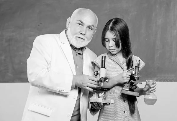 Chemical reactions research. mature teacher of biology. Pupil girl in school lab. science classroom. small girl with man tutor study chemistry. use magnifying glass. Microscopy. Laboratory equipment — Stock Photo, Image