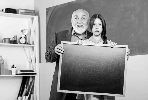 A mudança está aqui. quadro negro para informação e anúncio. Espaço para cópia. menina pequena com homem tutor estudo. Placa de giz vazia. Vendas escolares. sala de aula. professor maduro e menina aluna feliz — Fotografia de Stock