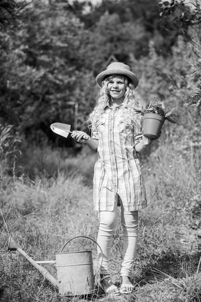 Kislány farmer gondozó üzem füvön. gazdálkodás és mezőgazdaság. Tavaszi szezon. Gyenge nyár. Egy kislány ásóval és öntözőkannával ültet. Földi nap. környezetvédelmi ökológia. természetvédelem — Stock Fotó