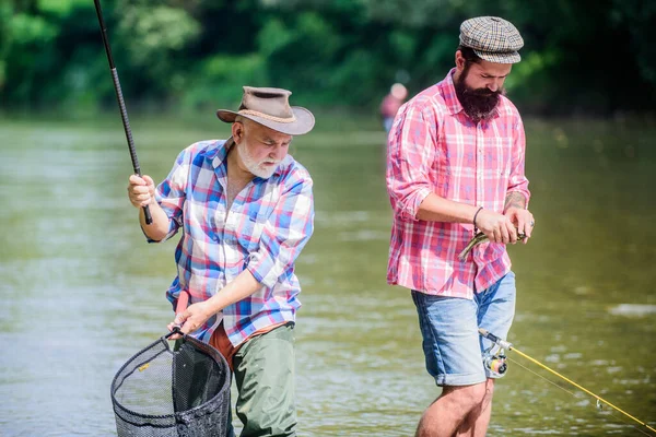 Feliz día. dos pescador feliz con caña de pescar y red. turismo de caza. padre e hijo pescando. Acampar en la orilla del lago. Pesca de caza mayor. amistad. Tiempo de pesca con mosca. pasatiempo — Foto de Stock