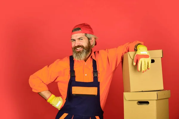 Umzug in eine neue Wohnung. Glücklicher Mann Karton. Kisten tragen im Gebäude. Umzugskartons auspacken. Neues Haus am Umzugstag. bärtige Bauarbeiter in Boilersuit halten Kisten — Stockfoto