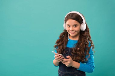 Küçük kız mp3 çalar tutuyor. En sevdiğin şarkıyı seç. Modern hayatta e-öğrenim. Liseli kız yeni teknoloji kullanıyor. kopyalama alanı. Çocuk kulaklıkla müzik dinliyor. Küçük çocuk akıllı telefondan çalma listesi yapıyor