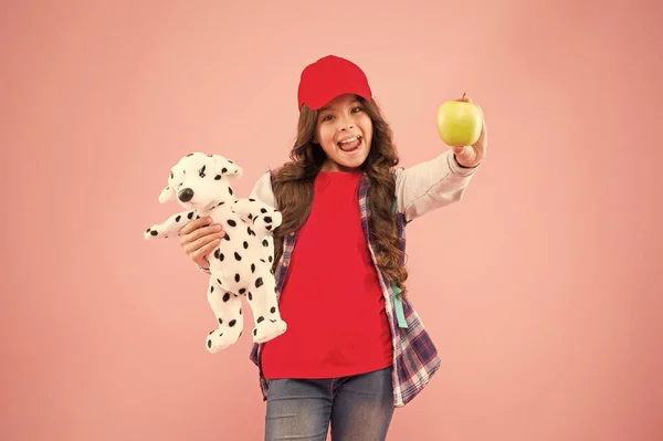Знизити стрес. Дівчинка маленька модна школярка з рюкзаком носить м'яку іграшкову собаку і тримає яблуко. Здоровий спосіб життя. Психічне та фізичне здоров'я. Школярка щоденне життя. Стильна школярка — стокове фото