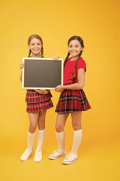 Aulas de claque. Escola meninas bonito pupilas vermelho uniforme segurar blackboard espaço de cópia. Conceito de anúncio escolar. Equipa de iniciativa de colegas. Junta-te ao clube. Comunidade de alunos. Horário escolar — Fotografia de Stock