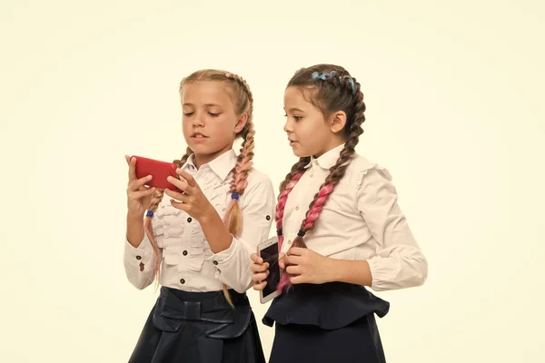 Modern life. Worldwide net. Internet resource has hazards for kids. Girls school uniform surfing internet. Schoolgirls use mobile internet smartphone. School application smartphone. Mobile addiction