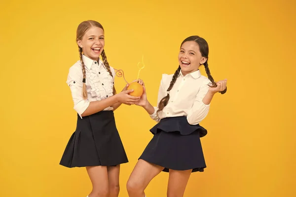 Een drink voedsel. Kleine meisjes genieten van vloeibaar vitamine voedsel op gele achtergrond. Kleine schoolkinderen die citrussap van sinaasappel vruchten drinken. Gezond biologisch voedsel. Veganistisch eten en drinken — Stockfoto