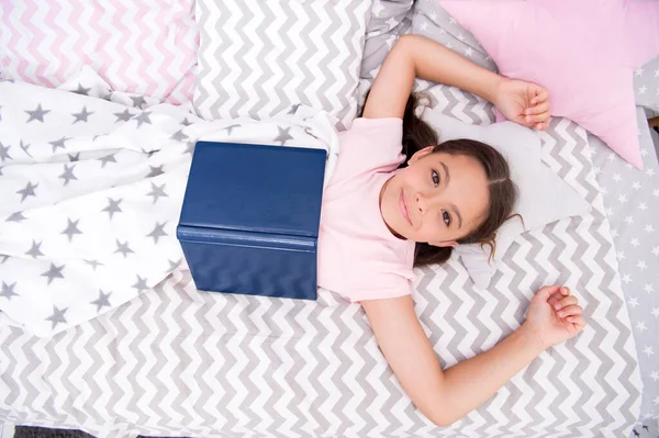 Must-have encyclopedia for every library. Happy girl read encyclopedia in bed. Small child with encyclopedia book. Encyclopedia facts and information for kids. Education and knowledge. Reference book — Stock Photo, Image