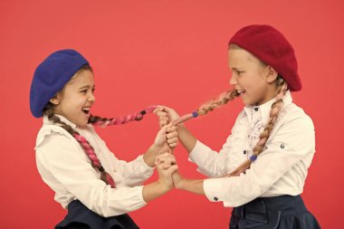 Zorbalık ve saldırganlık. Yaramaz çocuklar pembe arka planda at kuyruğu çekiyorlar. Zorbalık davranışları olan küçük kızlar bir çatışmayla savaşıyor. Okulda zorbalık. Zorbalığı durdurma zamanı