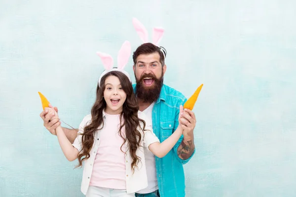 Jarní prázdniny. Oslavte Velikonoce. Velikonoční jídlo. Děvče a táta králičí uši. Šťastná rodina nosí králičí uši. Velikonoční zábava a štěstí. Otec a dcera si hrají s mrkví. Nakupování s potravinami. Vtipný tým — Stock fotografie