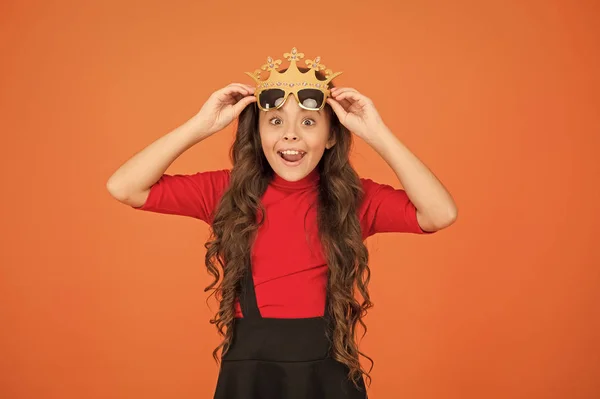 Wow, estoy sorprendido. Los niños sorprendidos llevan corona de utilería y gafas. Niño pequeño se ve sorprendido fondo naranja. Niña pequeña mantener la boca abierta con sorpresa. Estar sorprendido. Baile de graduación. Fiesta de celebración — Foto de Stock