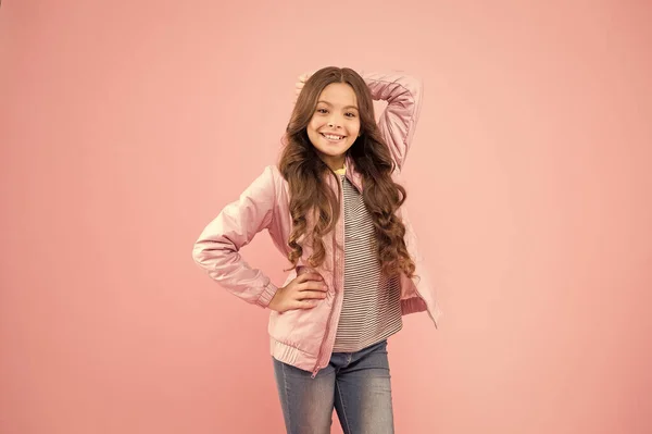 Lungo e riccio. Felice bambina con acconciatura lunga in stile autunnale. Adorabile bambino sorridente lunghi capelli castani su sfondo rosa. Styling capelli lunghi per la stagione autunnale — Foto Stock