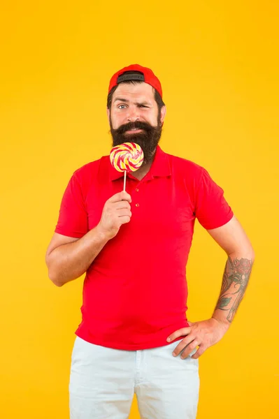 Un hombre divertido lamiendo piruletas. Hombre barbudo con piruleta. Asistente de tienda de dulces. dulce y confitero. Diversión piruleta. Lámelo. expresar emociones positivas. dulce gusto felicidad — Foto de Stock